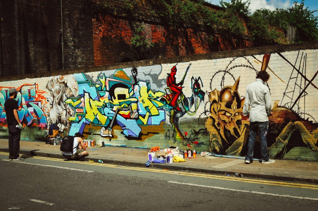 Artists create graffiti on a city wall.